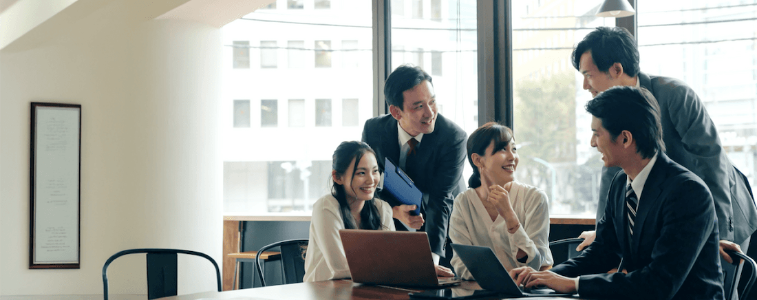 使用笔记本电脑和文件时,以明亮的办公室、智能和协作方式收集一张批处理的业务同事。