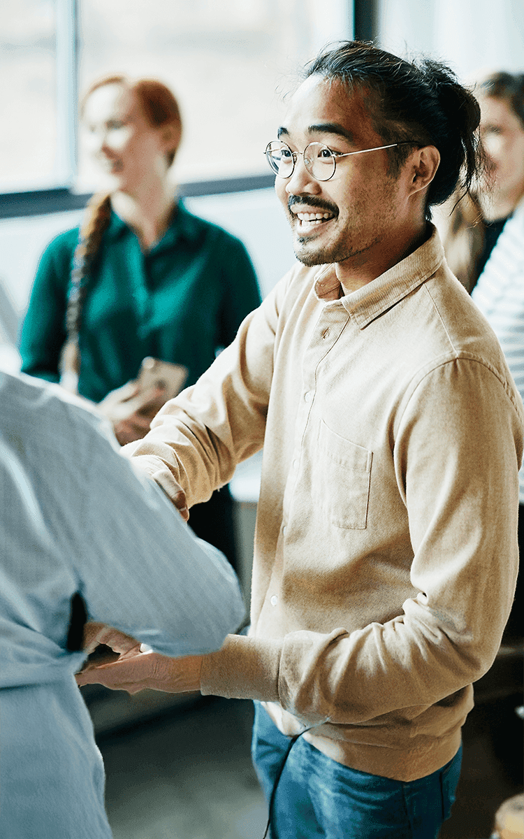 Three diverse colleagues smile while collaborating with their devices at a whiteboard.